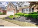 Exterior of a brick home boasting green landscaping and a white garage door at 1880 Hickory Station Cir, Snellville, GA 30078