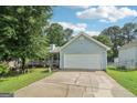 Light blue single-story home featuring a two-car garage, lovely porch, manicured lawn and mature trees at 1152 Sunday Ln, Jonesboro, GA 30238