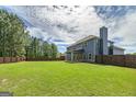 Large backyard featuring a wooden fence, lush green grass, and covered patio, perfect for outdoor activities and relaxation at 5016 Brass Ct, Locust Grove, GA 30248