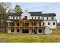 Expansive back of a white modern farmhouse featuring a covered porch and staircase at 3180 Lee Dr, Buford, GA 30518
