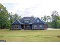 Attractive single-story house featuring a lush green lawn, stone details, and a charming front porch seating area at 227 Wet Wood Ct, Fairburn, GA 30213