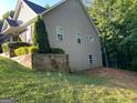 Exterior side view of home featuring landscaped retaining wall and vinyl siding at 565 Miles Ct, Locust Grove, GA 30248