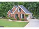 View of the side of a brick home showing mature landscaping and a drive-under garage at 5028 Chapel Lake Cir, Douglasville, GA 30135