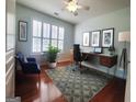 Bright home office with a modern desk, hardwood floors, and a comfortable sitting area bathed in natural light at 511 Bonneset Ct, Canton, GA 30114