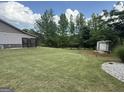 Expansive backyard with lush green grass, mature trees, and a storage shed at 411 Johnson Rd, Locust Grove, GA 30248