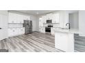 Modern kitchen with stainless steel appliances, white cabinetry, and granite countertops, complemented by stylish flooring at 3423 Arabian Farm Ln, Dacula, GA 30019