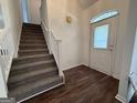 Bright foyer featuring hardwood floors, a staircase, and decorative front door at 7090 E Village Ct, Riverdale, GA 30296