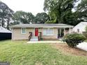 Exterior view of single-story home featuring a red front door and a covered parking area on the side at 2851 Mitchell Dr, Decatur, GA 30032