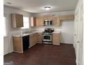 Functional kitchen with wooden cabinets, stainless steel appliances, and dark wood-look flooring at 6372 Stonebridge Creek Ln, Lithonia, GA 30058