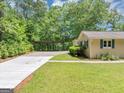 Driveway with carport for parking and the manicured front lawn with lush, mature landscaping at 4820 Yeager Rd, Douglasville, GA 30135