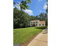Charming two-story home with well-manicured front yard and lush trees under a partly cloudy sky at 175 Forest Lake Dr, Fayetteville, GA 30215