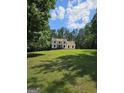 Charming two-story home with a well-manicured lawn, surrounded by lush trees, under a bright blue partly cloudy sky at 175 Forest Lake Dr, Fayetteville, GA 30215