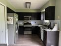 Modern kitchen with stainless steel appliances, dark cabinets, and tile backsplash at 150 Doe Run Ct, Sharpsburg, GA 30277