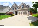 Two-story home with a large driveway and a two-car garage, surrounded by well-maintained landscaping at 613 Blackburn Ln, Peachtree City, GA 30269