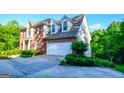 Lovely side view of a two-story brick home showcasing an attached two car garage and verdant landscaping at 155 Cottage Cir, Fayetteville, GA 30215