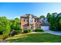 Attractive two-story brick home with green lawn, a two car garage, and mature landscaping at 155 Cottage Cir, Fayetteville, GA 30215
