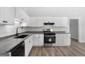 Bright kitchen featuring granite countertops, white cabinets, stainless steel appliances, and wood-look floors is modern and clean at 1404 Meadowind Court Sw, Conyers, GA 30094