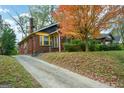 Brick home exterior showcasing a front yard tree with red-orange leaves and a long concrete driveway at 1660 Rogers Sw Ave, Atlanta, GA 30310