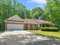 Charming single-story brick home with an attached two-car garage, manicured lawn, and mature trees surrounding the property at 175 N Unity Grove Rd, Locust Grove, GA 30248