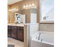 Luxurious bathroom with a soaking tub, double vanity, decorative lighting, and elegant finishes at 3970 Lagrone St, Powder Springs, GA 30127