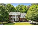 Beautiful two-story brick home featuring a double porch and lush greenery surrounding the property at 218 Woodruff Way, Peachtree City, GA 30269