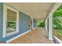 Long front porch with white columns and wooden floor offer plenty of space for relaxing and entertaining at 1128 Milstead Ne Ave, Conyers, GA 30012