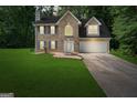 Two-story brick home at dusk with blue shutters, a two-car garage and well-maintained lawn at 96 Ashtonbrook Dr, Mcdonough, GA 30252
