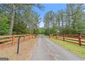 Long private driveway with a wooden fence and gate for added privacy and security at 1627 Leguin Mill Rd, Locust Grove, GA 30248