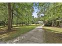 Long driveway through a tree-lined property leads to a charming home on a sprawling green lawn at 465 Crabapple Rd, Fayetteville, GA 30215