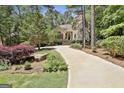 Stunning home nestled among trees featuring a stone chimney, stucco, and long driveway at 100 Rosemont, Peachtree City, GA 30269