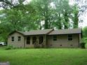 Charming brick home with a front porch, green lawn, and trees at 981 E Atlanta Rd, Stockbridge, GA 30281