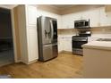 Modern kitchen featuring stainless steel appliances, white cabinets and countertops, and wood-look flooring at 235 Woodstream Way, Fayetteville, GA 30214