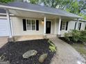 Inviting entrance featuring a covered porch, black mulch, and a well-manicured landscaped path at 6026 Woodcreek Dr, Woodstock, GA 30188