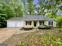 A charming tan home with a two-car garage and black shutters on the windows at 6026 Woodcreek Dr, Woodstock, GA 30188