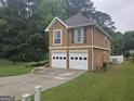 Side view of a brown two-story home featuring a two-car garage and landscaped yard at 320 Weatherly Drive, Fayetteville, GA 30214