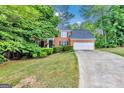 Traditional brick home featuring a manicured lawn, mature trees, and a spacious driveway at 4250 Edgewater Nw Ct, Kennesaw, GA 30144