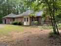 Rear exterior showcasing a brick home with a sunroom, side-entry garage, and private backyard setting at 115 Stable Creek Rd, Fayetteville, GA 30215