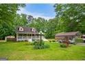 Expansive front yard showcasing the home, detached garage, carport, and lush greenery on a sunny day at 3777 Edward Rd, Rex, GA 30273