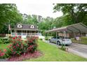 Home with carport, beautiful rose bushes, lush lawn, and American flag displayed at 3777 Edward Rd, Rex, GA 30273