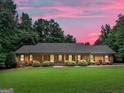 Beautiful dusk view of home with large lawn, mature trees, and charming covered front porch at 230 Shorewood Ct, Mcdonough, GA 30252