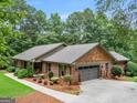 View of the home showing the attached garage, nice yard, and brick and cedar shake siding at 230 Shorewood Ct, Mcdonough, GA 30252
