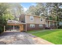 Inviting two-story home with a covered carport and a quaint front porch, surrounded by lush greenery and a well-maintained lawn at 115 Fairview Way, Stockbridge, GA 30281