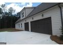 Spacious three-car garage with dark doors, exterior lighting, and a large driveway at 49 Durham Estates Dr, Sharpsburg, GA 30277