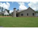 View of rear of house with well-maintained lawn, black trimmed windows, and chimney at 49 Durham Estates Dr, Sharpsburg, GA 30277