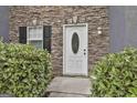 Close up of a charming home entrance with a white front door, stone facade, and manicured greenery at 122 Claxton Ct, Jonesboro, GA 30238
