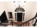 View from the top of a staircase facing a front door with large arched window and decorative chandelier above at 232 Spalding Gates Drive, Atlanta, GA 30328