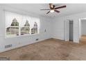 Bright living room featuring neutral carpeting, a ceiling fan, and a large window at 2609 Lake Harbin Rd, Morrow, GA 30260