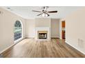 Spacious living room featuring a fireplace, large window, ceiling fan, and beautiful wood-look flooring at 5669 Blackberry Row, Ellenwood, GA 30294