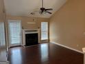 Open living room with a fireplace, fan, and hardwood floors with lots of natural light at 95 Revere Turn Drive, Fairburn, GA 30213