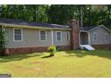 Ranch-style home featuring a brick chimney and base, with a tidy front lawn and landscaped features at 142 Carrollwood Dr, Fayetteville, GA 30215